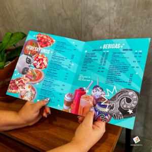 Imprenta y Diseño Gráfico en Guadalajara | Escala Gráfica Persona sosteniendo un menú plegable para restaurante con diseño a color e impresión de alta definición.